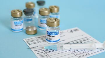 Close-up image of vaccine vial and syringe on CDC covid-19 vaccination record card